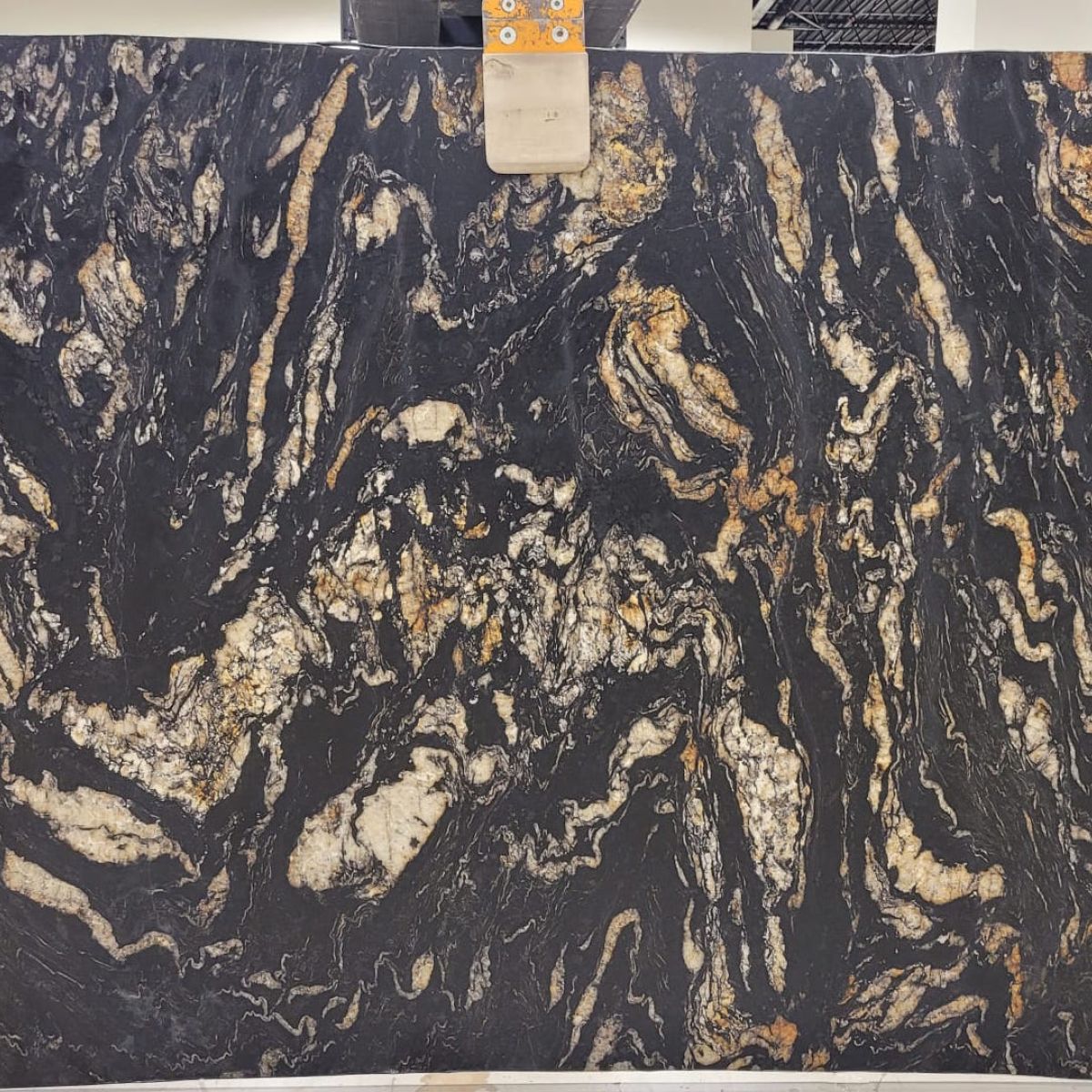 Titanium Gold Leathered Granite granite slab with deep gold and bronze movement, full slab on the rack at StoneX USA, West Allis WI