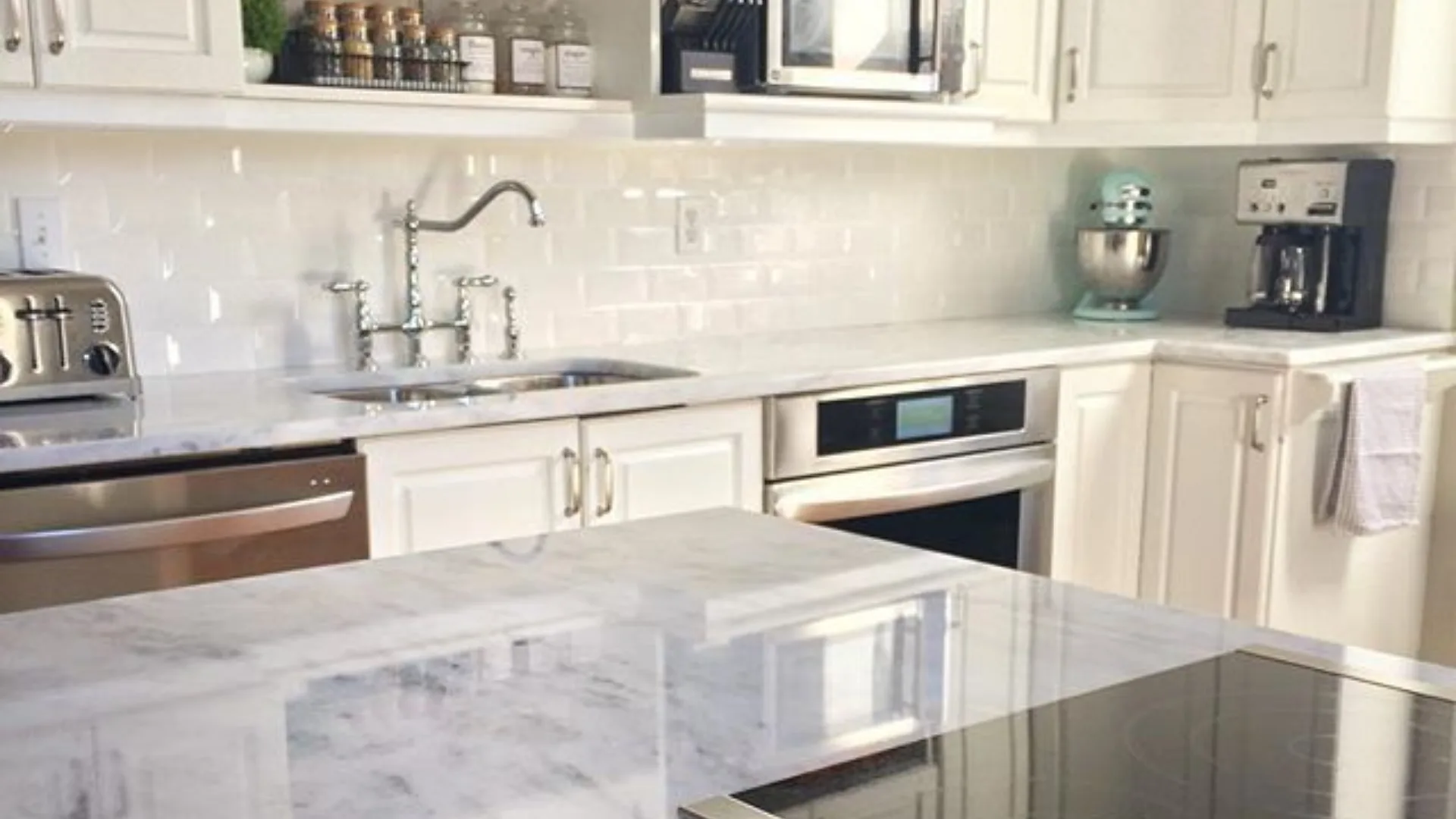 White kitchen with a light veined stone countertop and subway tile backsplash